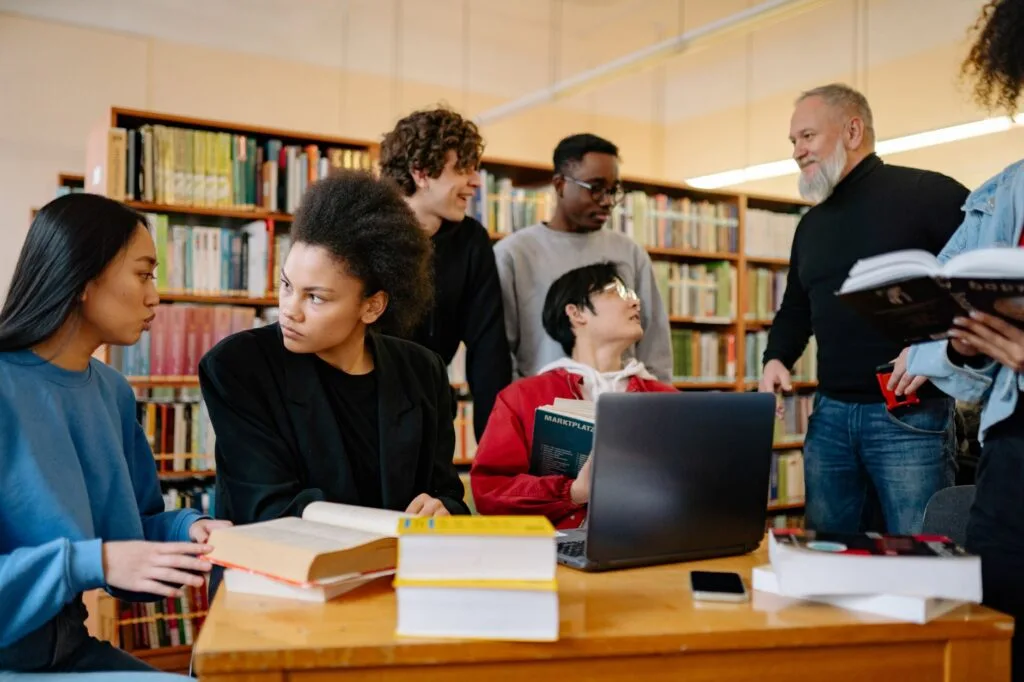 Sekelompok penulis mengerjakan naskah bersama di perpustakaan kampus